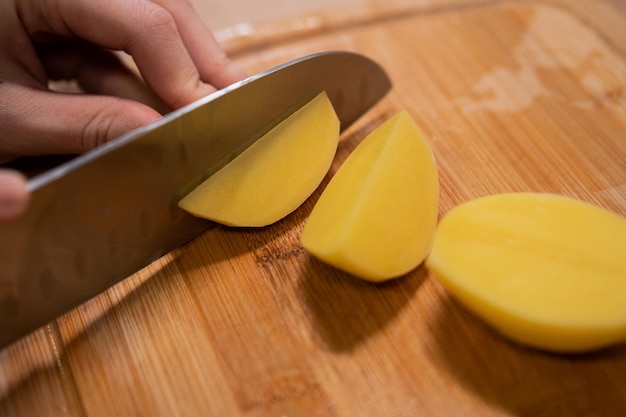 写真 健康的な食品の準備を調理する金属製のナイフで生のジャガイモを手で切る
