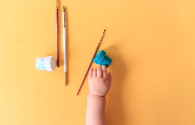 Рука ребенка, рисующего линии и формы разноцветными мелками.