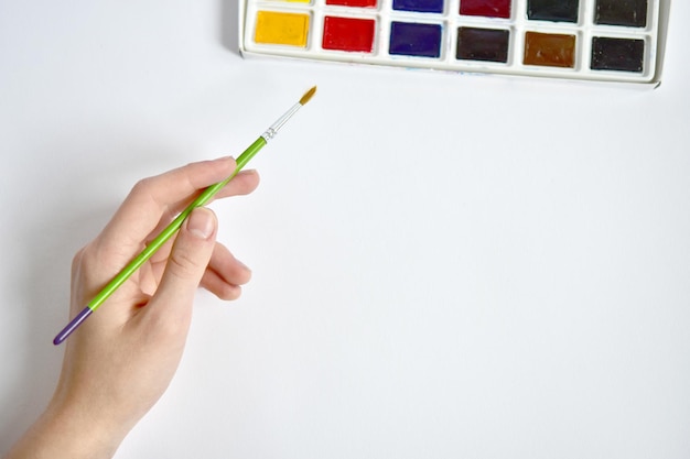 Фото Рука с кистью тянется к акварели макет для художественного произведения живопись красками