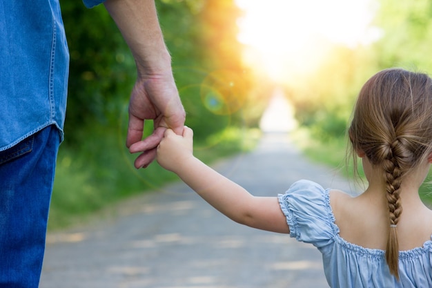 A Handen van gelukkige ouder en kind op de natuur op de weg op de achtergrond van het park