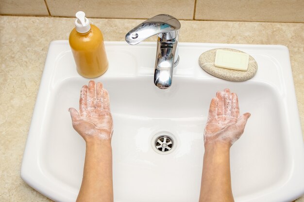 A Handen wassen met zeep onder de kraan met water