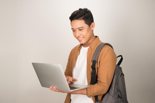 Красивый молодой студент с ноутбуком и рюкзаком на белом фоне