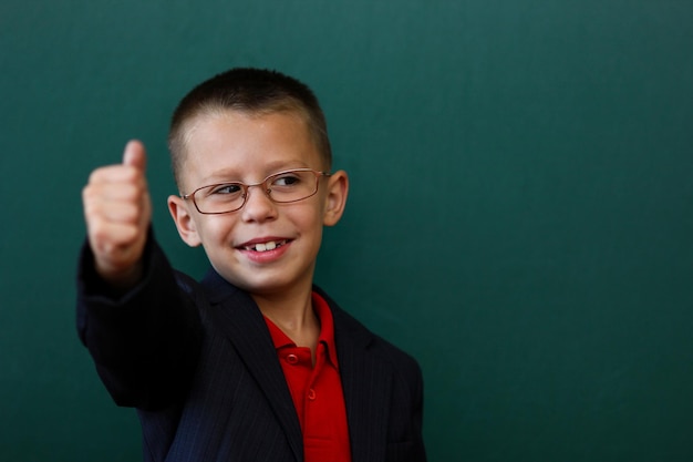 안경을 쓴 학교 배낭을 메고 칠판에 서 있는 행복한 아이