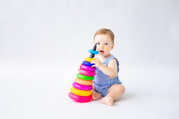 写真 幸せな小さな幼児の男の子は、白い背景で隔離のカラフルなピラミッドのおもちゃで遊んでいます子供たちの子供の発達のための知育おもちゃ