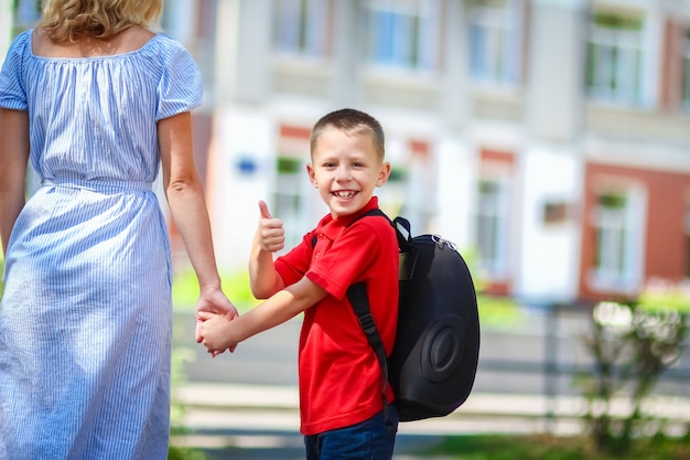 写真 幸せなお母さんが学校に戻る途中で子供を学校に連れて行く