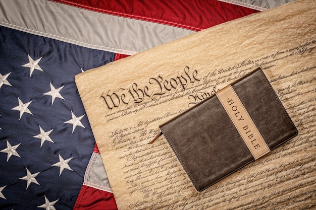 Фото Священная библия и распятие покоятся на конституции соединенных штатов и американском флаге, что символизирует свободу вероисповедания без преследований.