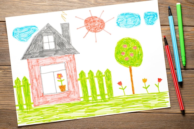 Фото Дом забор цветы и яблоня детский рисунок на бумаге деревянный стол фломастерами