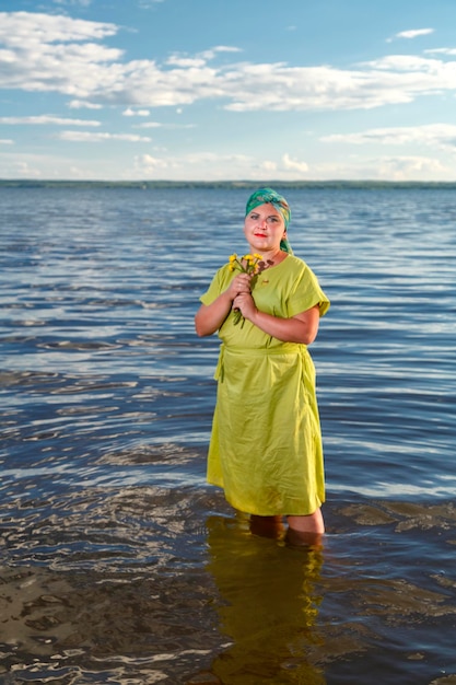 Фото Еврейская женщина в зеленом платье и платке в озере по колено в солнечный день