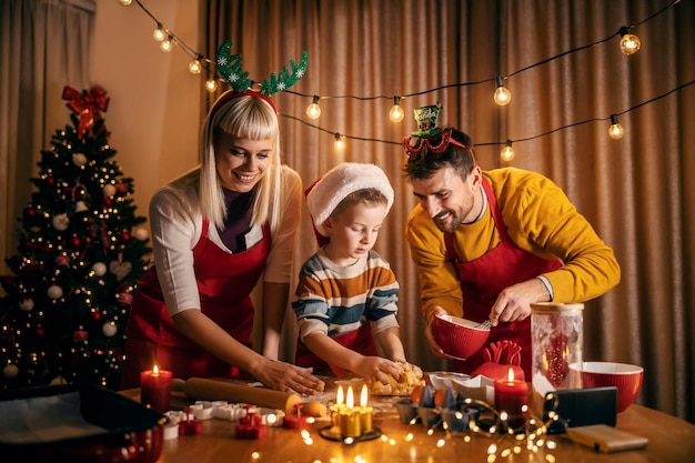 写真 喜ばしい両親は ⁇ クリスマスの暖かい家で息子と一緒にジンジャーブレッドクッキーを料理しています ⁇