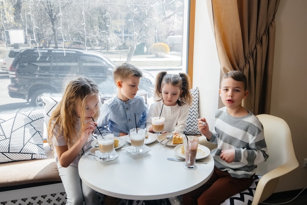 Фото Большая дружная компания детей отмечает праздник в кафе с вкусным десертом. день рождения