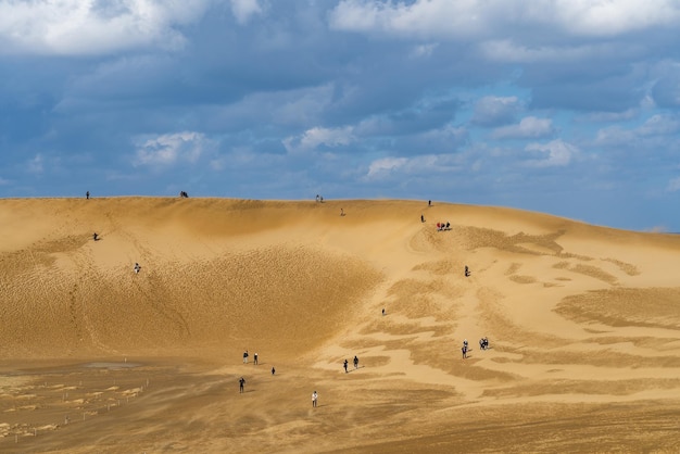 Фото Большая песчаная дюна с людьми, стоящими на вершине и несколькими людьми на вершине тотори сэнд