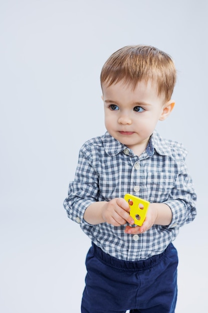 Фото Годовалый мальчик на белом фоне с развивающей деревянной игрушкой экологические деревянные игрушки для маленьких детей развитие ребенка