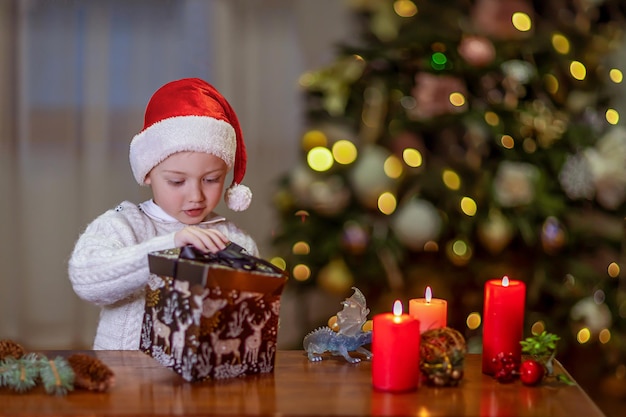 写真 小さな男の子が木の下で見つけたクリスマスプレゼントが入った箱を開ける