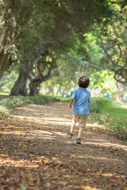사진 파란 셔츠를 입고 공원에서 달리는 작은 소년
