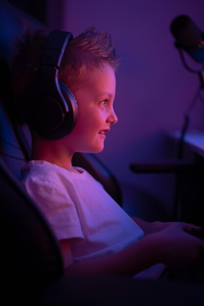 写真 ヘッドフォンとマイクを持った小さな男の子がコンピューター ゲームをプレイします コンソール ゲームをストリーミングします