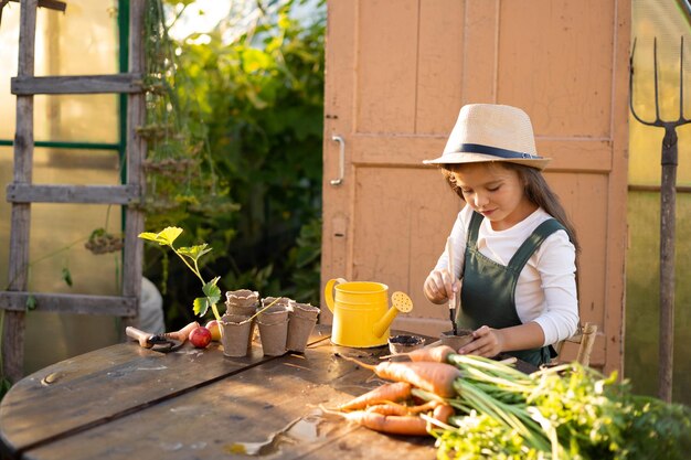 写真 少しかわいい長髪の農家の女の子が植物の植え付けに取り組んでいます 村の菜園 ガーデニング エコロジー