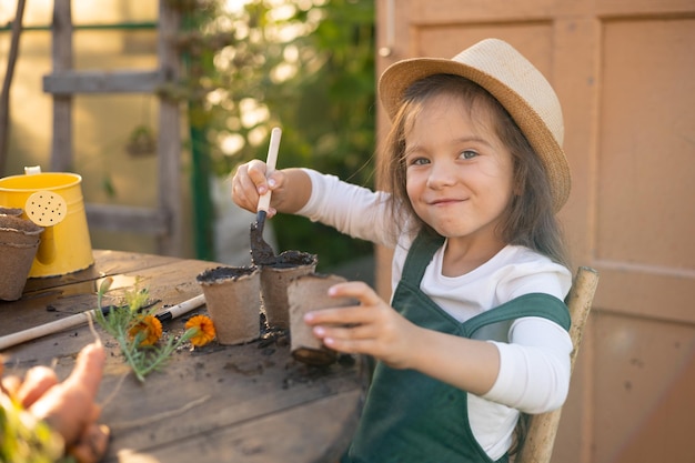 写真 少しかわいい長髪の農家の女の子が植物の植え付けに取り組んでいます 村の菜園 ガーデニング エコロジー