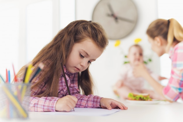 写真 小さな女の子がキッチンの上に色鉛筆で描きます。