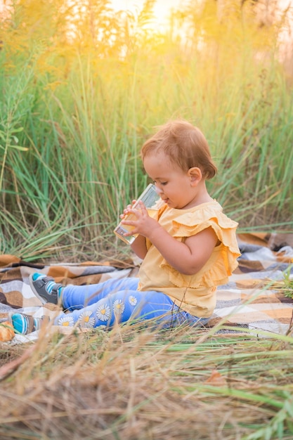 写真 ピクニックでリンゴジュースを飲む少女