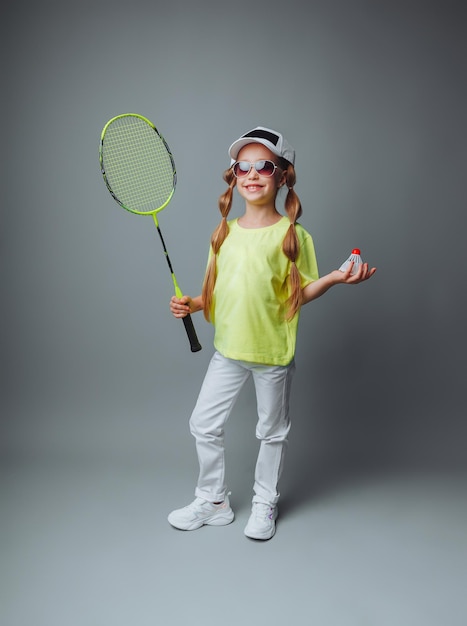 Фото Маленькая девочка держит ракетку на сером фоне маленький теннисист маленький ребенок играет в теннис детские спортивные состязания