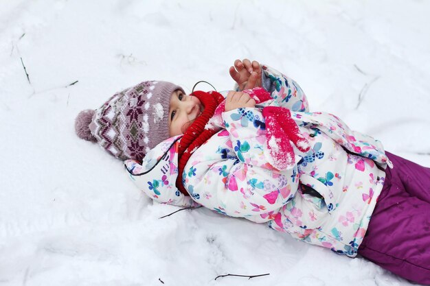 写真 小さな女の子が雪の中で遊んでいます