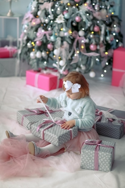 写真 小さな女の子が床に座って、プレゼントと一緒にクリスマスボックスを開梱します。