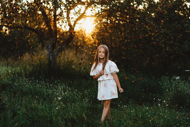 写真 夕暮れ時に小さな女の子が庭を歩く