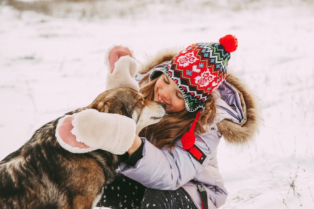 Фото Маленькая девочка гуляет со своей собакой в зимнем лесу.
