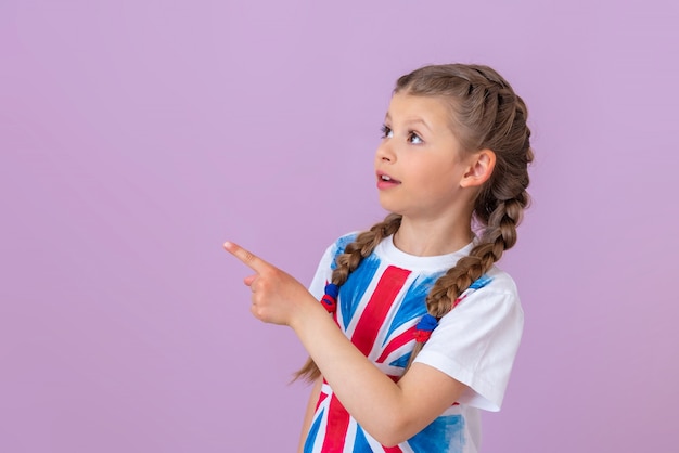 땋은 머리를 한 어린 소녀와 티셔츠에 영국 국기의 이미지가 손가락으로 옆을 가리키고 있습니다.