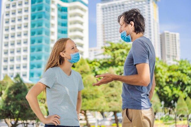 Фото Мужчина и женщина общаются на улице с неправильно ношенными масками. неправильное ношение медицинских маск.
