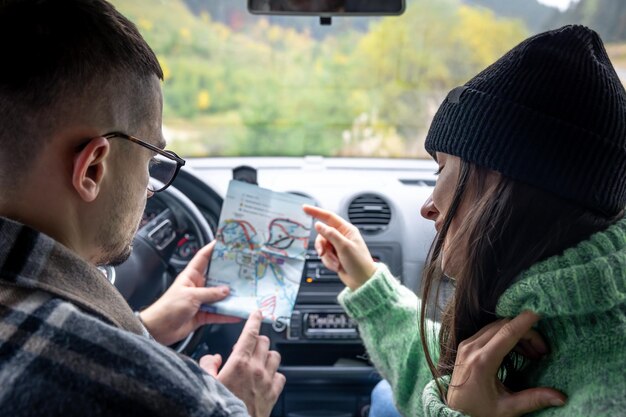 写真 車の中に座って紙の地図を持って見ている男性と女性