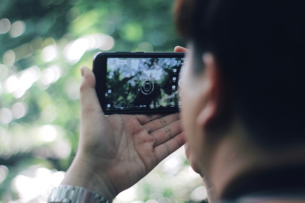 写真 スマートフォンを持っている男が写真を撮る