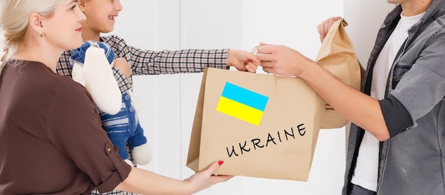 写真 ウクライナとロシアの間の戦争に巻き込まれたウクライナ難民と貧しい市民のために、ある男性が援助の箱を持っています。人道援助の概念難民に寄付する