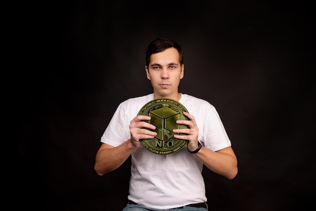Фото Мужчина держит в руках монету neo как символ технологии