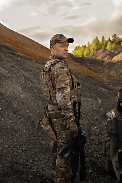 Фото Человек в военной форме с atv и пулеметом в руках стоит в горах