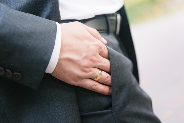 写真 スーツを着た男性が結婚指輪を膝の上に置いています。