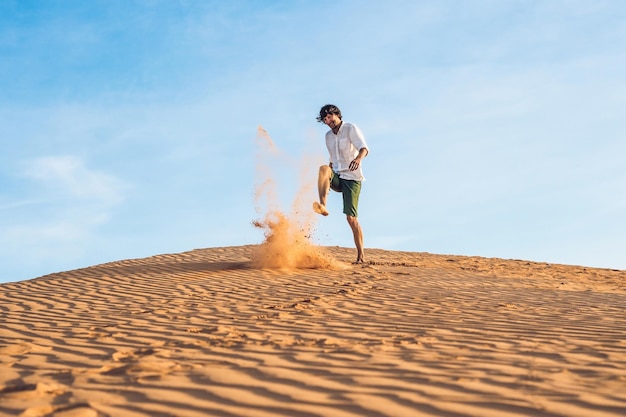 写真 男が赤い砂漠で砂を蹴っている。怒りの概念のスプラッシュ