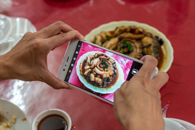 한 남자가 손에 휴대전화를 들고 사진을 찍고 있다