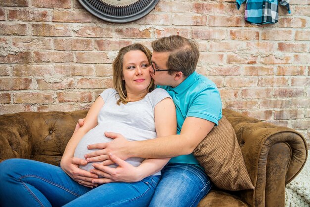 사진 임신한 여자를 키스하는 남자 임신한 여자에게 키스하는 남자가 앉아 있습니다.
