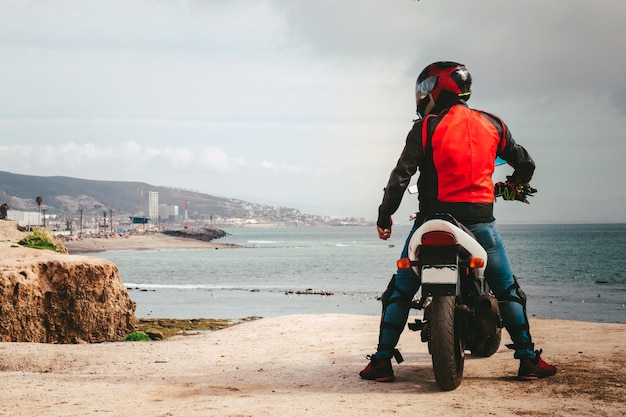 Фото Мужчина на мотоцикле смотрит на море.