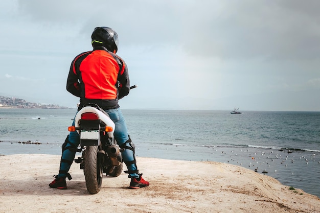 Фото Мужчина на мотоцикле смотрит в море.