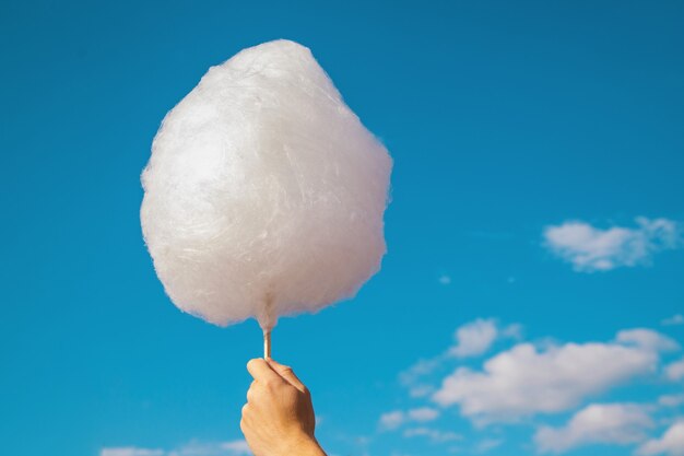 https://img.freepik.com/premium-photo/a-man-s-hand-holds-cotton-candy-against-a-blue-sky-white-cotton-wool-like-a-cloud_277130-487.jpg?size=626&amp;ext=jpg