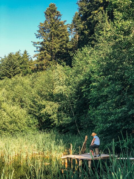 Фото Мужчина стоит возле озера в лесу