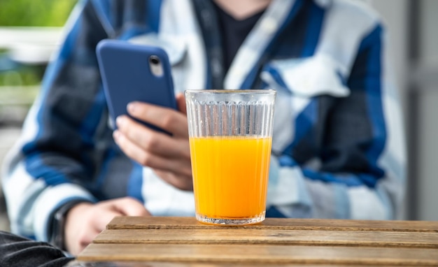 Мужчина пользуется смартфоном и пьет апельсиновый сок