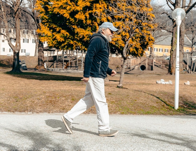 写真 男が家を背景に木の前の歩道を歩いています。