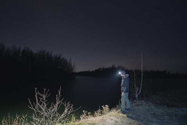 写真 低照明で川の近くの自然の中で夜にヘッドランプを持った男性 高品質の写真