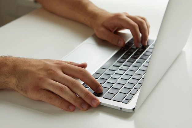 Фото Мужчина работает на ноутбуке, его руки закрываются