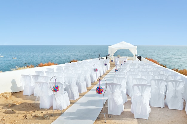 사진 결혼식을위한 장식과 꽃의 놀라운 장소. 바다에 하얀 의자가 있습니다.