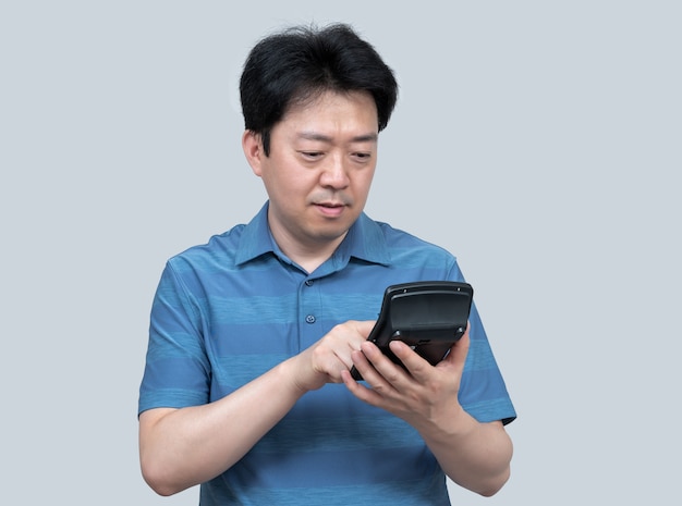 Азиатский мужчина средних лет держит в руке калькулятор