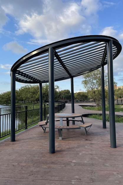 写真 池の岸にある市内の公園のテーブルとベンチを持つ現代的なスタイリッシュなガゼボまたはキャノピー